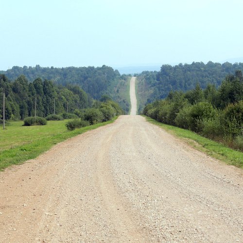 summer landscape dirt road among meadows and forests