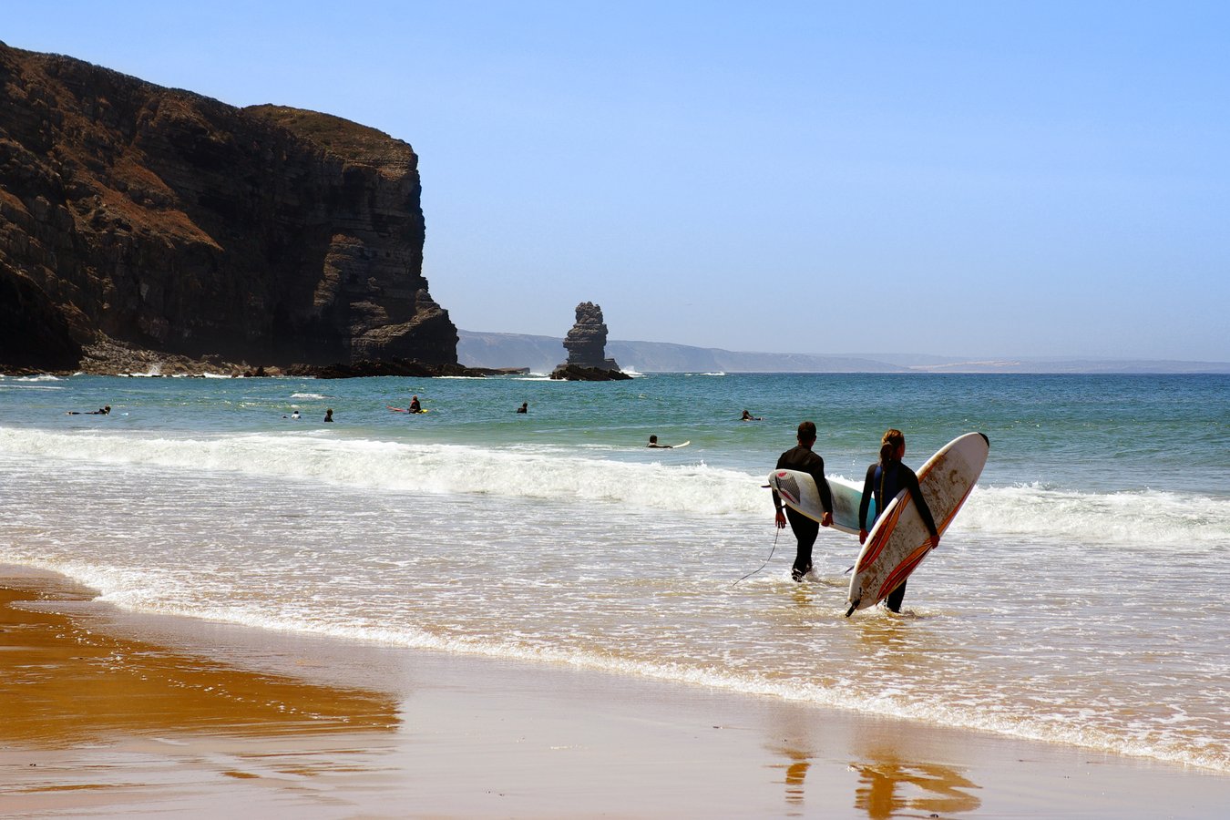 surfers ready to enter the sea in arrifana beach, algarve portugal.